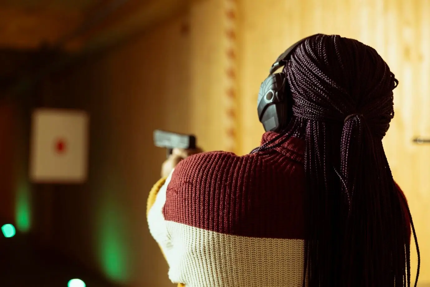 Eine Frau im Schießstand nutzt eine Pistole, um Ziele zu treffen, und trägt Schutzausrüstung.