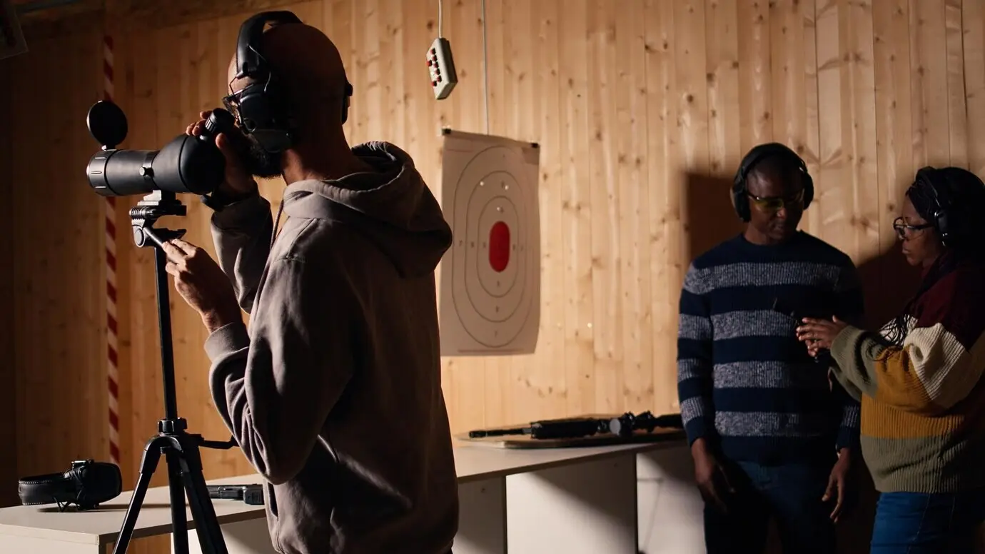 Eine Person analysiert während des Schießtrainings mit einer Lupe die beschossenen Zielscheiben.